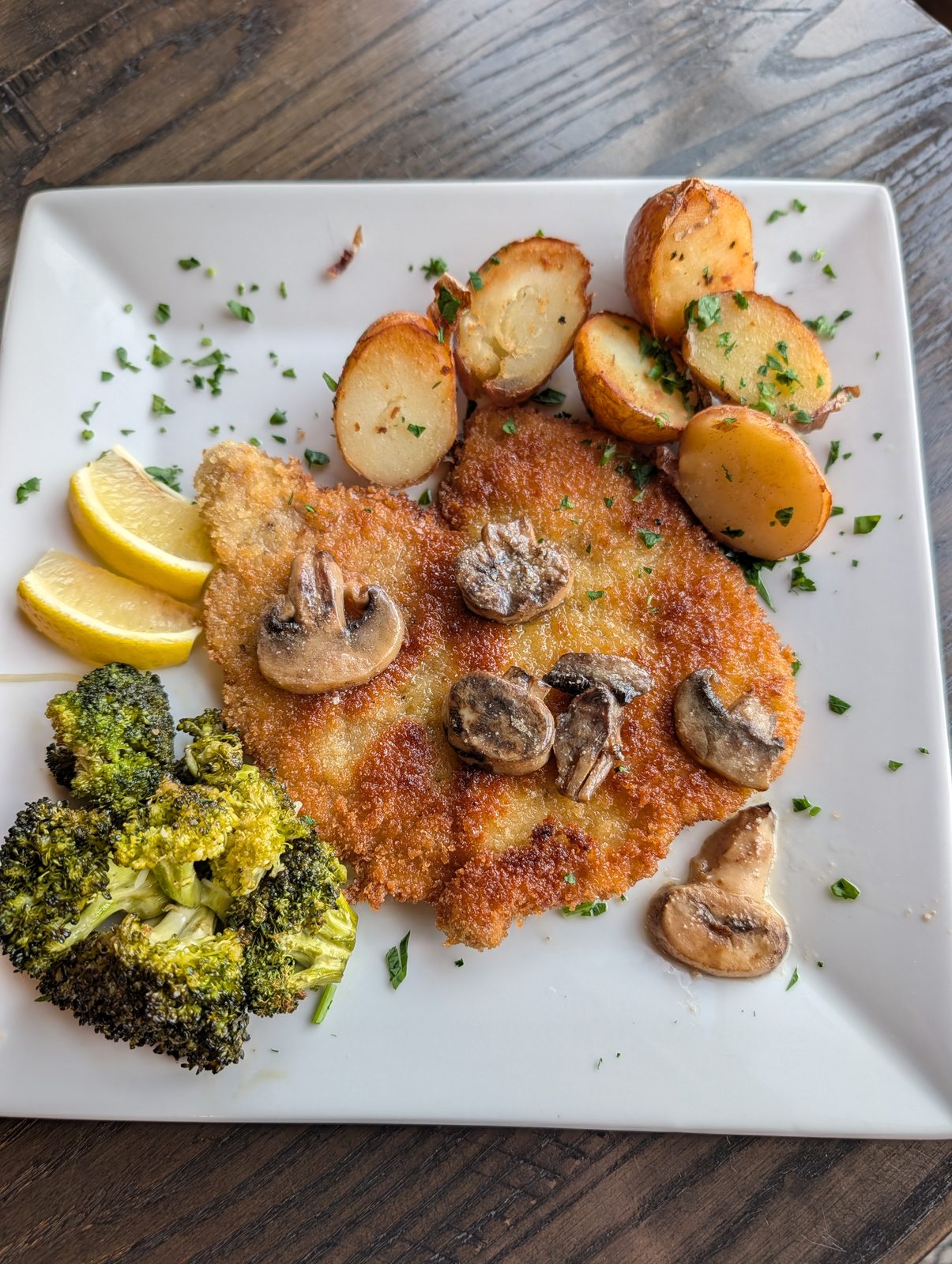 Crispy breaded cutlet topped with saut&eacute;ed mushrooms, with roasted potatoes and broccoli