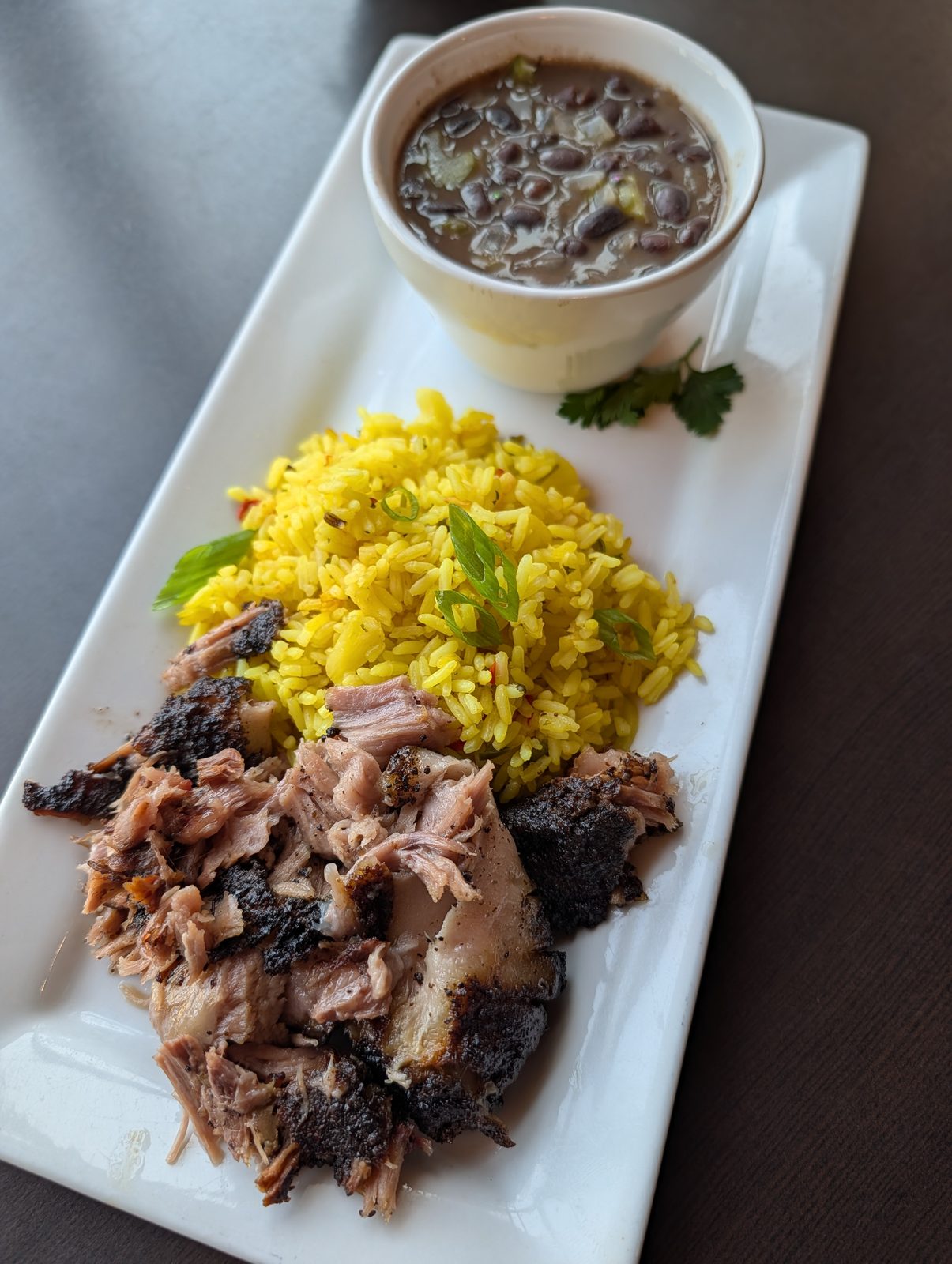Mojo pulled pork with yellow rice and a cup of black beans