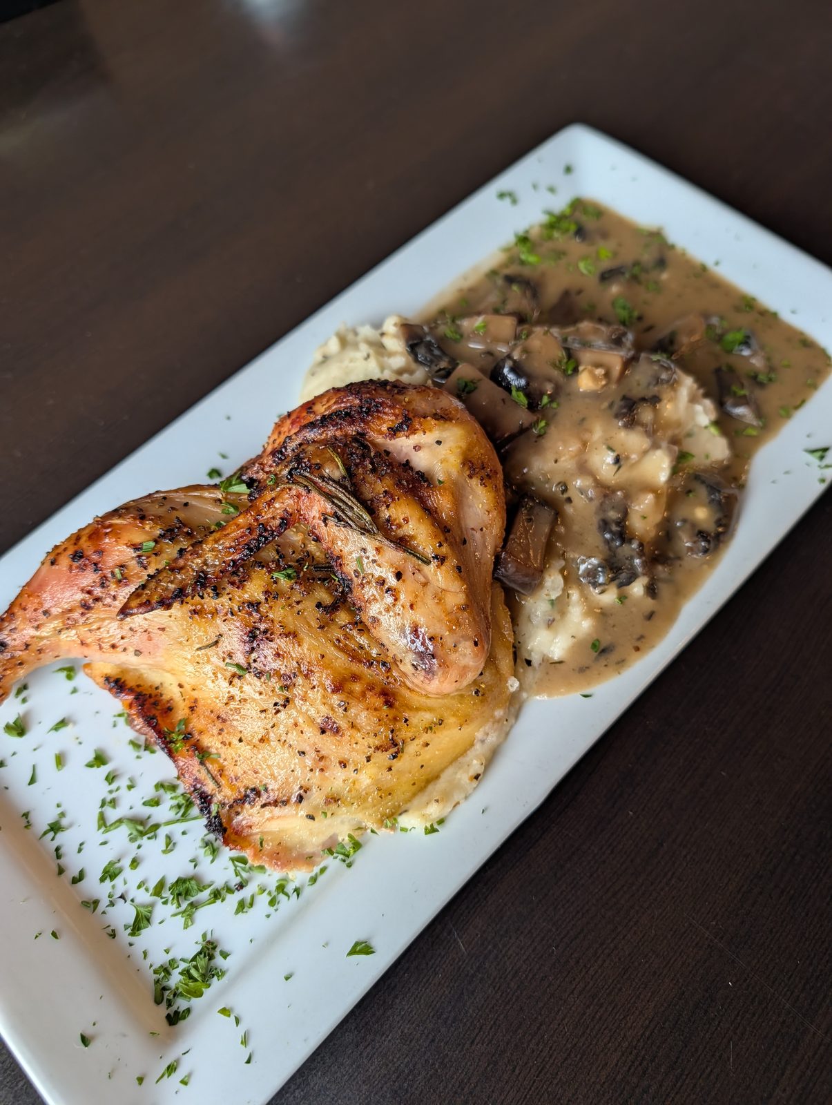 Rosemary roasted half chicken over mashed potatoes with mushroom gravy